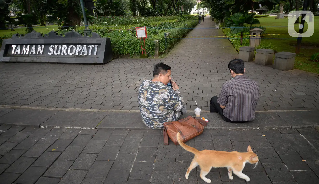 Warga sedang duduk diluar pembatas tulisan tanda ditutup sementara untuk mencegah penyebaran virus Covid-19 di Taman Suropati, Menteng, Jakarta, Senin (21/12/2020). (merdeka.com/Dwi Narwoko)