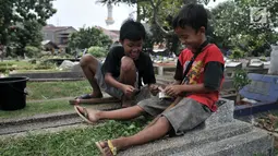 Sejumlah anak saat membagi hasil dari jasa 'Ngoret' makam di TPU Cipinang Baru, Jakarta, Minggu (5/5). Anak-anak 'Pengoret' makam mengaku dapat mengantongi uang hingga Rp 70 ribu dari hasil ngoret yang dimulai pagi sampai sore. (merdeka.com/Iqbal S. Nugroho)