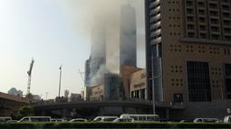 Jalanan di sekitar lokasi kebakaran ditutup, seiring membumbungnya asap hitam tebal dari lokasi kejadian, Uni Emirat Arab, Minggu (2/4).  Belum ada laporan jatuhnya korban tewas atau luka dari peristiwa kebakaran tersebut. (AP Photo/ Maggie Hyde)