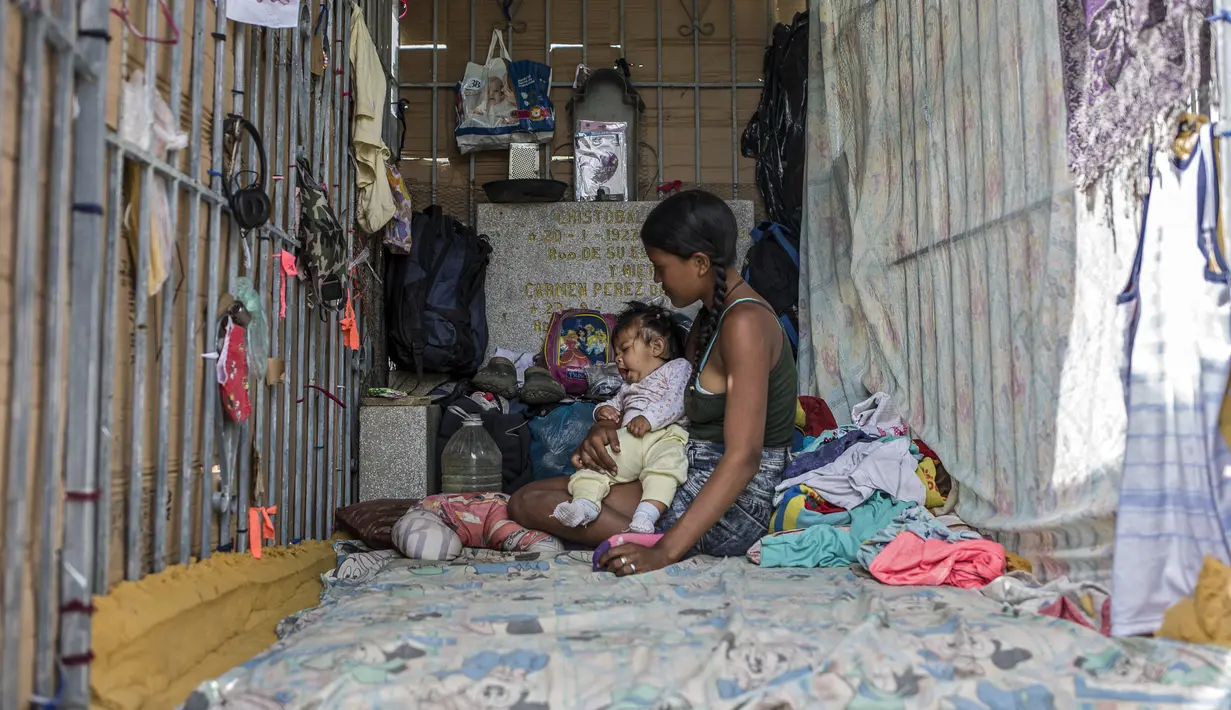 Seorang perempuan muda dan bayi beristirahat di tempat perlindungan darurat di Pemakaman Umum Selatan di Caracas, pada 16 Februari 2021. Makam yang dirusak telah menjadi rumah bagi banyak tunawisma di Venezuela. (Pedro Rances Mattey / AFP)
