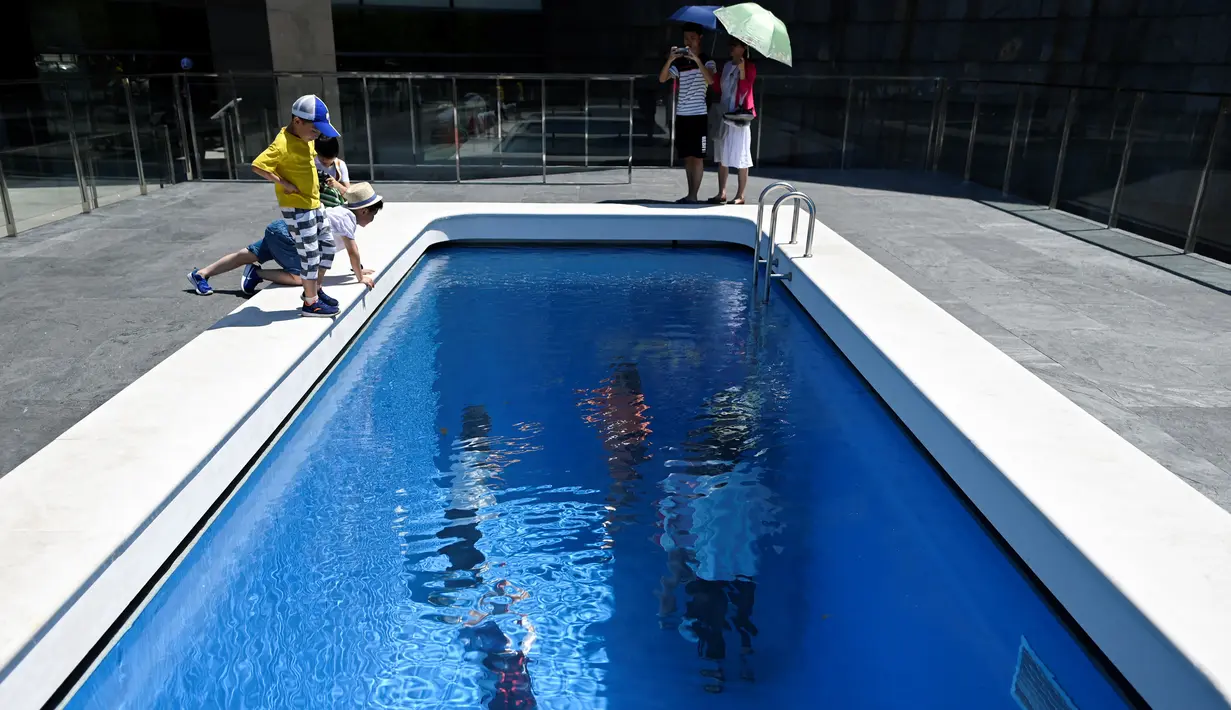 Pengunjung melihat karya seni Swimming Pool dalam sebuah pameran bertajuk "The Confines of the Great Void" di Museum CAFA, Beijing, 23 Juli 2019. Karya seni buatan seniman Argentina, Leandro Erlich ini tampak seperti kolam renang pada umumnya yang penuh dengan air. (WANG Zhao/AFP)