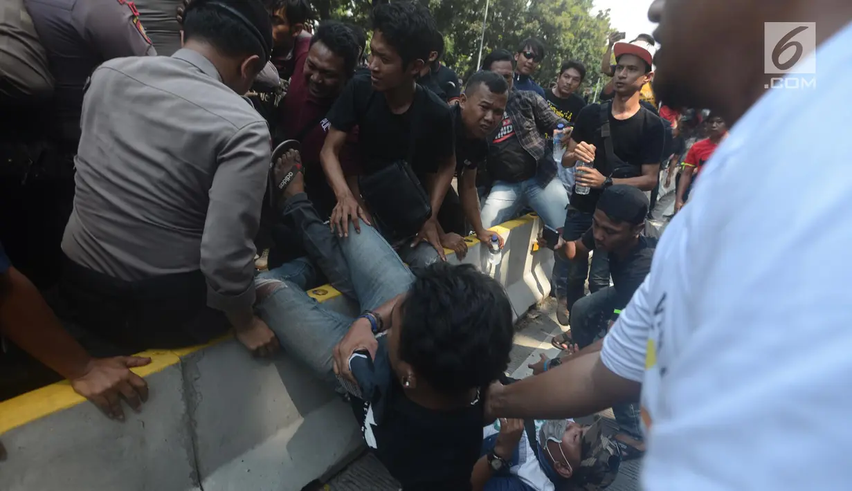 Dua orang pria terjatuh saat terjadi aksi saling dorong antara polisi dan massa driver taksi online yang tergabung dalam Aliando di Jalan Medan Merdeka Barat, Jakarta, Rabu (28/3). (Merdeka.com/Imam Buhori)