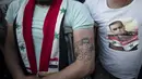 Seorang tentara Suriah yang terluka dengan tato Presiden Bashar Assad saat mereka merayakan kemenangannya di Omayyad Square, di Damaskus, Kamis (27/5/2021). Bashar al-Assad terpilih kembali untuk masa jabatan keempat sebagai presiden Suriah yang dilanda perang. (AP Photo/Hassan Ammar)