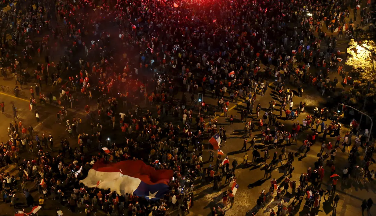 Sejumlah suporter berjalan bersorak membawa bendera nasional Chili merayakan kemenangan Chili atas Argentina di final Copa Amerika 2015 di Santiago, (4/7/2015). Chili menang lewat adu penalti atas Argentina dengan skor 4-1. (REUTERS/Carlos Garcia Rawlins)