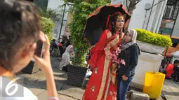 Seorang pengunjung berpose dengan wanita berkostum ala Tionghoa saat mengunjungi Kota Tua, Jakarta, Jumat (8/7). Kota Tua menjadi salah satu pilihan masyarakat Jakarta ataupun luar Jakarta, untuk mengisi libur lebaran. (Liputan6.com/Gempur M Surya)