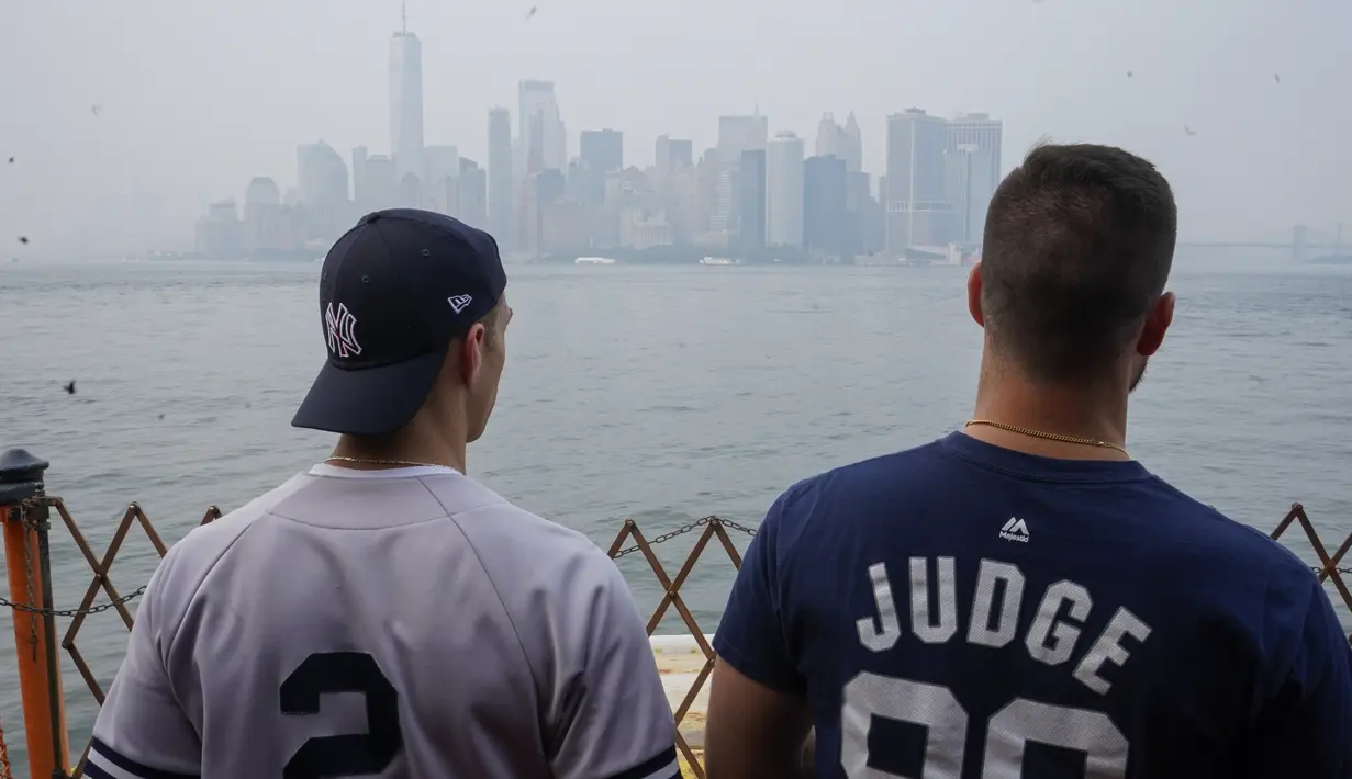 Para penumpang Staten Island Ferry melihat pemandangan Manhattan yang terlihat melalui kabut, di New York, Selasa (20/7/2021). Asap dari kebakaran hutan di seluruh AS Barat, termasuk Oregon's Bootleg Fire, telah mengepul di sebagian besar wilayah timur Amerika Serikat. (AP Photo/Mary Altaffer)