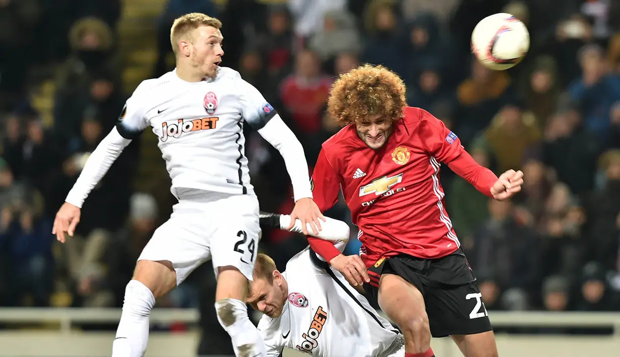 Gelandang Manchester United, Marouane Fellaini, duel udara dengan pemain FC Zorya Luhansk. Dalam pertandingan ini MU melakukan delapan kali pelanggaran dan dua di antaranya berbuah kartu kuning. (AFP/Sergei Supinsky)