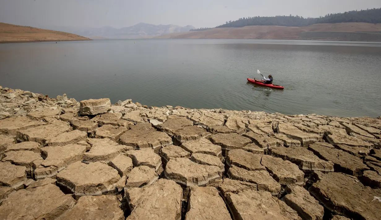 Seorang kayaker memancing di Danau Oroville saat ketinggian air masih rendah akibat kondisi kekeringan yang terus berlanjut di Oroville, California, Minggu (228/2021). Kekeringan ekstrem di California telah membuat ketinggian air di danau tersebut terus menurun. (AP Photo/Ethan Swope)