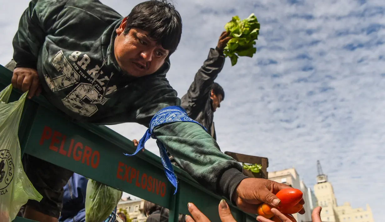 Petani membagikan sayuran secara gratis saat demonstrasi petani di alun-alun Plaza de Mayo dekat Istana Presiden Casa Rosada di Buenos Aires, Senin (24/4). (AFP FOTO / Eitan ABRAMOVICH)