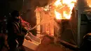 Imigran berusaha memadamkan api yang membakar kamp mereka di lahan kumuh yang dijuluki "Jungle" di Calais, Prancis (1/3). Kamp ini berpenghuni sekitar 3.000 pengungsi dan pencari suaka. (REUTERS/Pascal Rossignol)