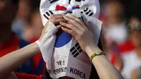 Seorang warga menutupi wajahnya dengan bendera Korea Selatan usai timnasnya dikalahkan Belgia 0-1, Seoul, Jumat (27/6/14). (REUTERS/Kim Hong-Ji)