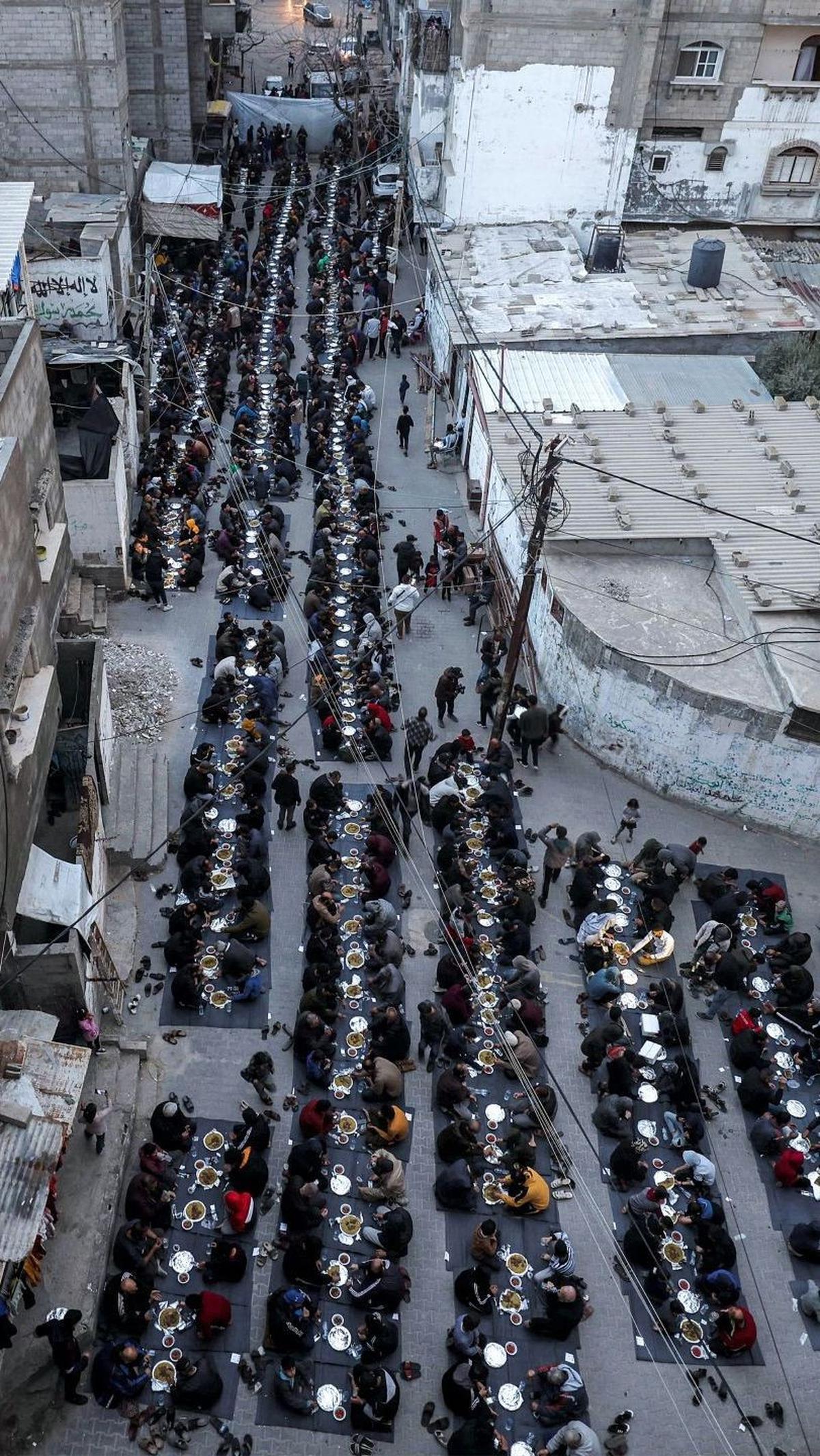 Acara buka puasa massal ini diselenggarakan oleh anggota kamp pengungsi Barbara, di sepanjang jalan Kota Rafah di Jalur Gaza selatan pada 24 Maret 2024.&nbsp;Foto: MOHAMMED ABED / AFP<br>