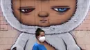 Seorang wanita mengenakan masker untuk membantu mengekang penyebaran COVID-19 saat berjalan melewati mural di Bangkok, Thailand, Selasa (20/7/2021). Dari 13.002 kasus COVID-19 terbaru di Thailand, sebanyak 1.049 di antara narapidana. (AP Photo/Sakchai Lalit)