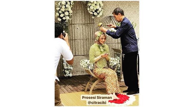 Sang ayahanda menyiramkan air ke tubuh Ciki. Ia pun berdoa sambil meminta restu kepada orangtuanya.