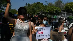 Sejumlah wanita Myanmar memakai gaun pengantin memegang plakat selama demonstrasi menentang kudeta militer 1 Februari di Yangon (10/2/2021). Aksi unjuk rasa terus digelar para demonstran yang mengabaikan larangan demonstrasi oleh militer. (AFP/ Ye Aung Thu)