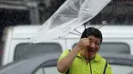 Seorang pria Taiwan memperbaiki payungnya saat melawan angin kencang yang ditimbulkan oleh topan Lekima di Taipei, Taiwan (9/8/2019). Topan Lekima saat ini tengah menghantam Taiwan, membawa angin ribut dengan kecepatan 190 km/jam. (AP Photo / Chiang Ying-ying)