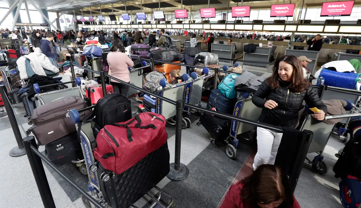 Penumpang maskapai Avianca menunggu penerbangan yang tertunda di Bandara Internasional John F Kennedy (JFK), New York, Senin (8/1). Banjir yang menimpa bandara tersebut menambah kesemrawutan yang terjadi beberapa hari belakangan. (AP/Richard Drew)