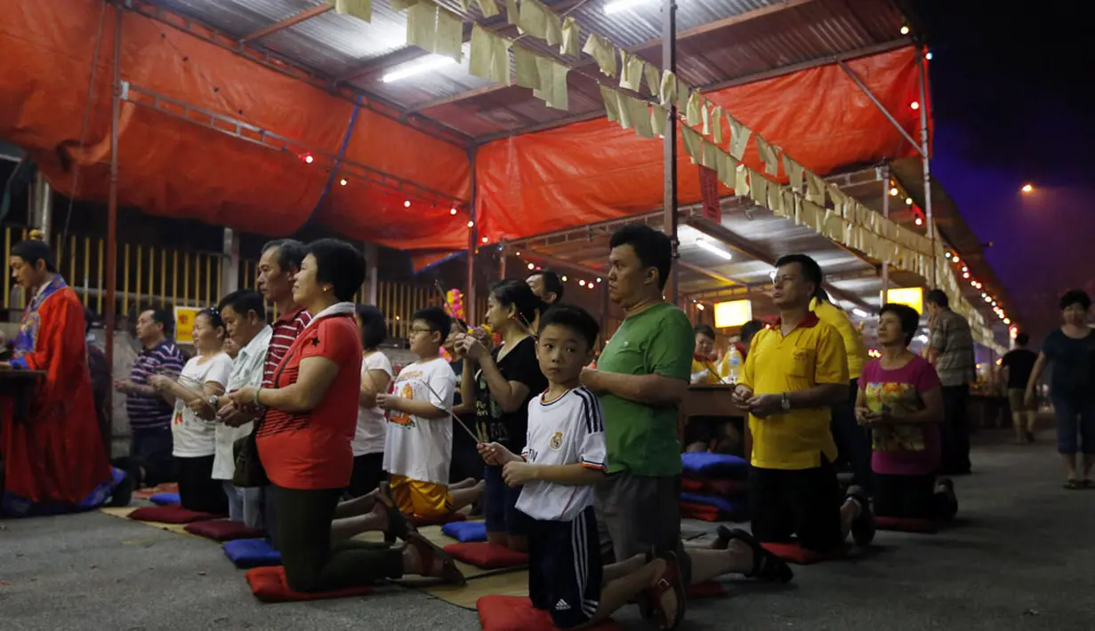 Menurut Tao dan keyakinan Budha, bulan ketujuh dalam kalender Imlek Tiongkok dikenal sebagai festival Hungry Ghost. Beberapa warga keturunan Tiongkok berdoa saat festival Hungry Ghost, (3/8/2014). (REUTERS/Olivia Harris)