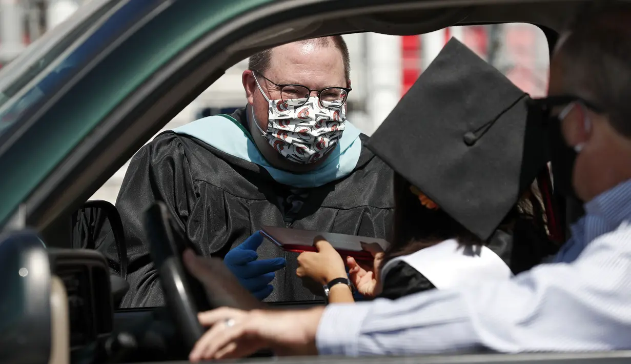 Kepala Sekolah Vance Fishback memberikan ijazah kepada mahasiswa Cabarrus Early College of Technology saat menjalani wisuda di Charlotte Motor Speedway, Concord, North Carolina, Amerika Serikat, Jumat (12/6/2020). Ribuan mahasiswa menjalani wisuda di arena NASCAR. (AP Photo/Gerry Broome)