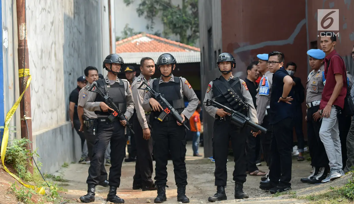 Polisi bersenjata berjaga-jaga saat berlangsungnya olah TKP di rumah terduga teroris di Nanggewer, Cibinong, Bogor, Jawa Barat, Sabtu (18/5/2019). Densus 88 Antiteror Mabes Polri menggelar olah TKP di rumah terduga teroris E alias Abu Rafi alias Pak Jenggot (51). (merdeka.com/Imam Buhori)