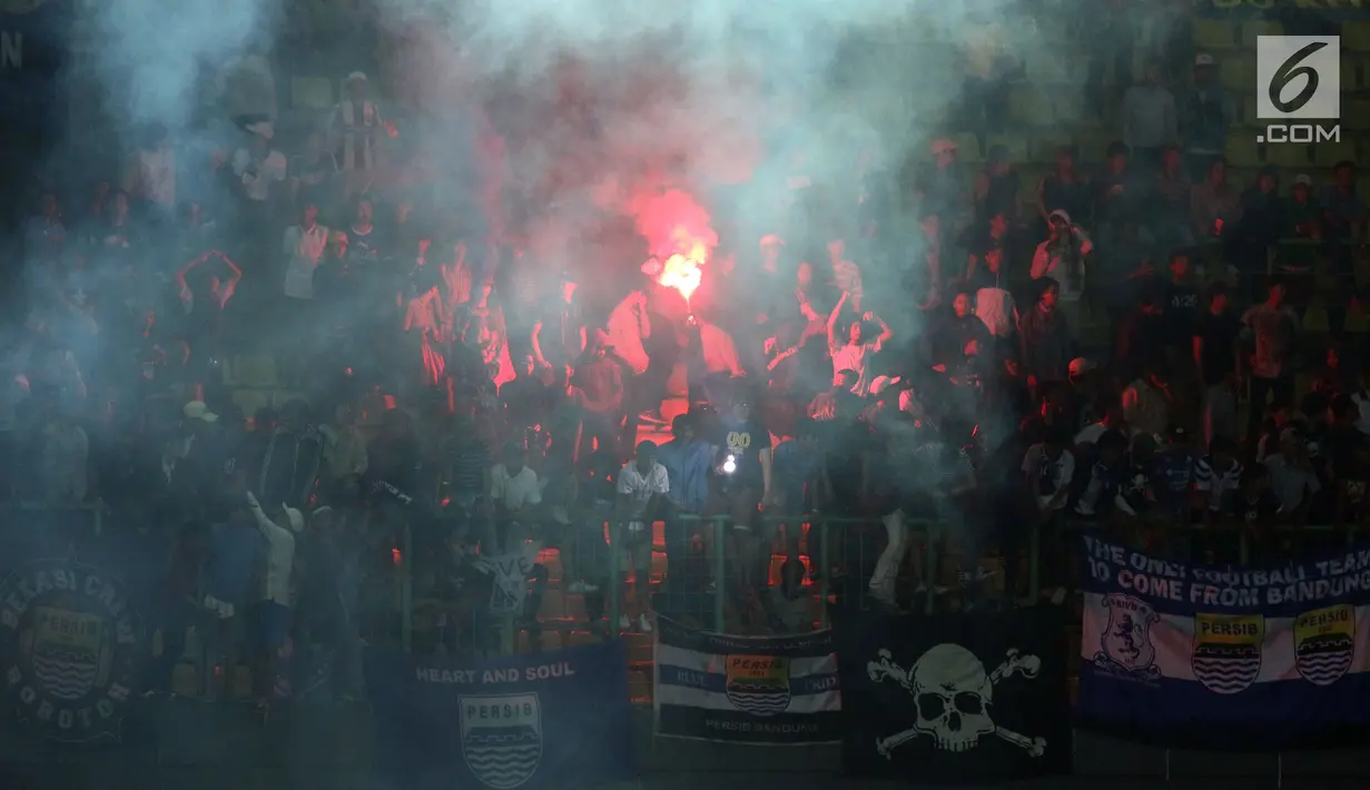 Suporter tim Maung Bandung menyalakan suar saat menyaksikan laga Bhayangkara FC melawan Persib di Stadion Patriot Candrabhaga, Bekasi, Minggu (4/6). Persib kalah 0-2 dari Bhayangkara FC. (Liputan6.com/Helmi Fithriansyah)