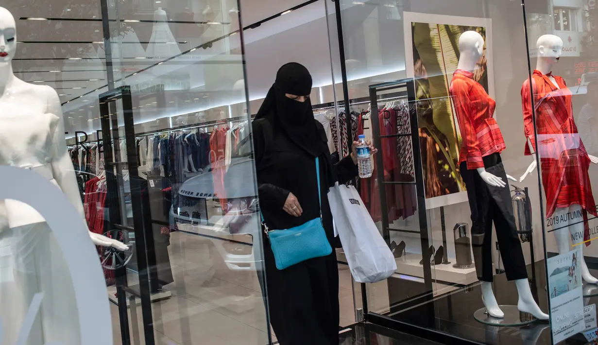 Seorang wanita yang mengenakan niqab meninggalkan toko pakaian setelah berbelanja di Istanbul, Turki, 13 Agustus 2018. Para turis dari negara-negara Arab rela antre hingga ke luar toko demi mendapatkan barang bermerk dengan harga murah. (AFP/Yasin AKGUL)