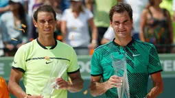 Roger Federer (kanan) dan Rafael Nadal berpose dengan trofinya di Crandon Park, Florida (2/4). Bagi Federer, ini adalah titel ketiganya di Miami atau yang pertama dalam 11 tahun usai memenanginya di 2005 dan 2006. (AP Photo/Wilfredo Lee)