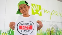 Seorang anak menunjukkan kaos bertuliskan "Autism is Not a Joke" saat acara Fun Walk 2015 di Balaikota DKI Jakarta, Minggu (29/3/2015). (Liputan6.com/Herman Zakharia)