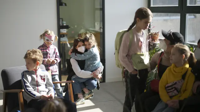 Anak-anak pengungsi dari Ukraina menunggu dengan ibu mereka untuk memulai kelas mereka di Berlin, Jerman, Senin (21/3/2022). Kedua kelas privat pengungsi tersebut disatukan oleh dua relawan Berlin yang berhasil menggalang dana dan mendapatkan ruang kelas gratis. (AP Photo/Markus Schreiber)