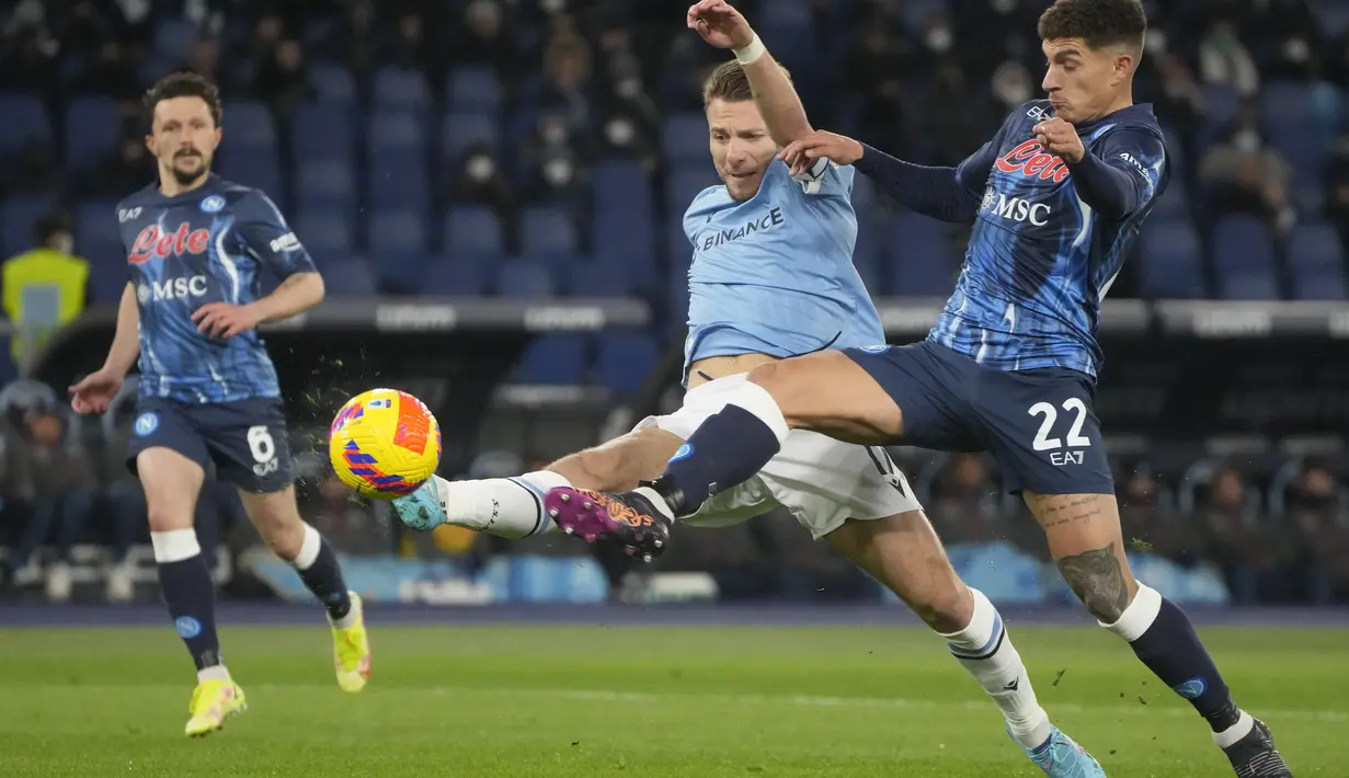Penyerang Lazio, Ciro Immobile (kiri) berebut bola dengan gelandang Napoli, Giovanni Di Lorenzo pada pertandingan Liga Serie A Italia di stadion Olimpiade Roma, Senin (28/2/2022). Dengan kemenangan ini, Napoli berhasil memuncaki klasemen sementara dengan 57 poin. (AP Photo/Gregorio Borgia)