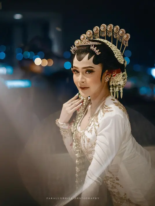 Penampilan luar biasa Bella Bonita di acara akad nikahnya dengan Denny Caknan. Pengantin Jawa yang manglingi dengan kebaya putih berpayet emas, paes pengantin yang lengkap dengan cunduk mentul hingga ronce bunga melatinya. [Foto: Instagram/faralljibrill_official]