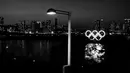 Cincin Olimpiade bercahaya mengapung di air di bagian Odaiba Tokyo, (6/3/2020). (AP Photo/Jae C. Hong)
