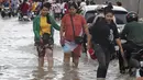 Pekerja garmen pergi ke tempat kerja melalui jalan yang banjir setelah hujan di  Phnom Penh, Kamboja (14 /10/2020). Pejabat bencana Kamboja mengatakan bahwa lebih dari 10.000 orang telah dievakuasi ke tempat aman setelah badai tropis melanda yang menyebabkan banjir bandang.  (AP Photo/Heng Sinith)