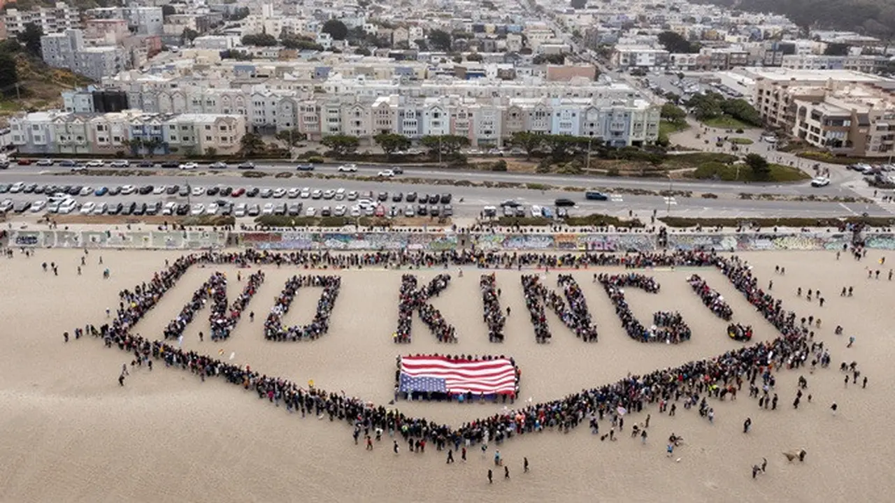 Sekelompok orang membentuk spanduk manusia di Pantai Ocean, San Francisco, Amerika Serikat, dalam unjuk rasa "No Kings" pada Sabtu, (14/6/2025).