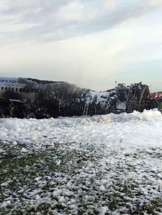 Pesawat Sukhoi Superjet-100 milik maskapai Aeroflot dikelilingi oleh busa dari pemadam kebakaran setelah melakukan pendaratan darurat dan terbakar di Bandara Sheremetyevo, Moskow, Rusia, Minggu (5/5/2019). Investigasi digelar untuk menyelidiki insiden tersebut. (Moscow News Agency photo via AP)