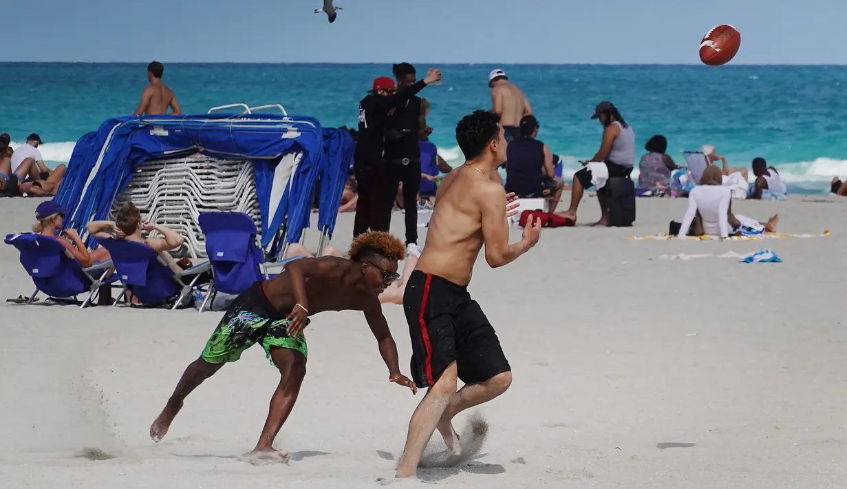 Orang-orang bersenang-senang di pantai di Miami, Florida pada Selasa (16/3/2021). Mahasiswa telah tiba di daerah Florida Selatan untuk liburan musim semi tahunan. Para pejabat kota prihatin dengan kerumunan liburan musim semi saat pandemi COVID-19 terus berlanjut. (Joe Raedle/Getty Images/AFP)