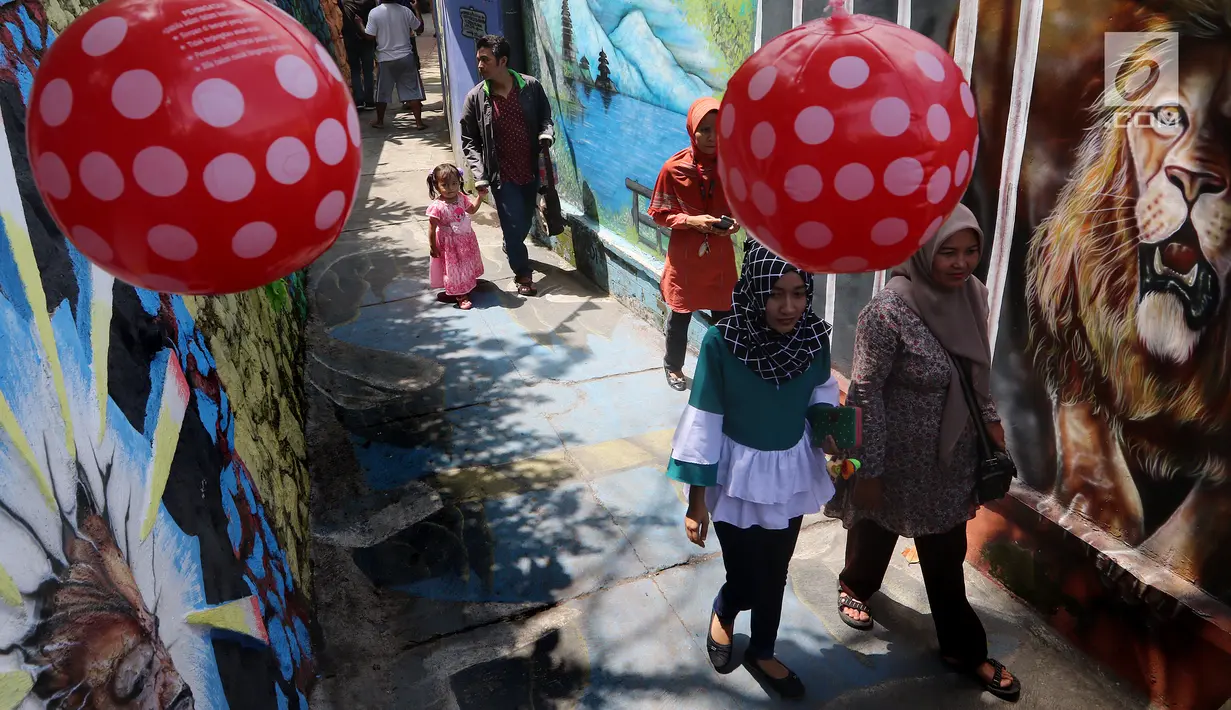 Wisatawan melintas di kampung warna-warni Kelurahan Kesatrian, Kota Malang, Minggu (5/11). Wisatawan dikenakan tiket masuk Rp2000 untuk perawatan lingkungan. (Liputan6.com/Fery Pradolo)