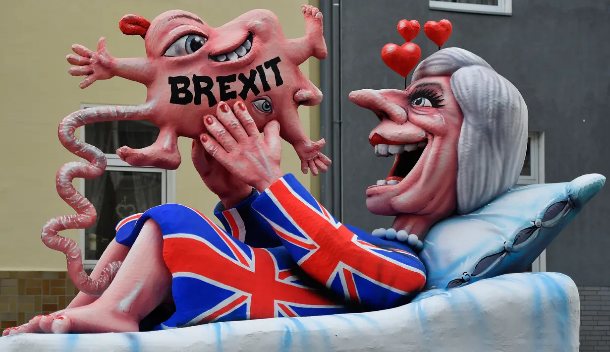 Kereta karnaval membawa karikatur yang menggambarkan Perdana Menteri Inggris, Theresa May melahirkan bayi Brexit-nya dalam parade karnaval Rose Monday di Duesseldorf, Jerman, Senin (12/2). (AP Photo/Martin Meissner)