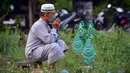 Seorang pria berdoa di sebelah makam kerabat saat perayaan Hari Raya Idul Adha di sebuah pemakaman di Provinsi Narathiwat, Thailand, Rabu (21/7/2021). Setiap Idul Adha atau hari besar Islam lainnya, sebagian warga banyak mendatangi kuburan untuk mendoakan keluarganya. (Madaree TOHLALA/AFP)