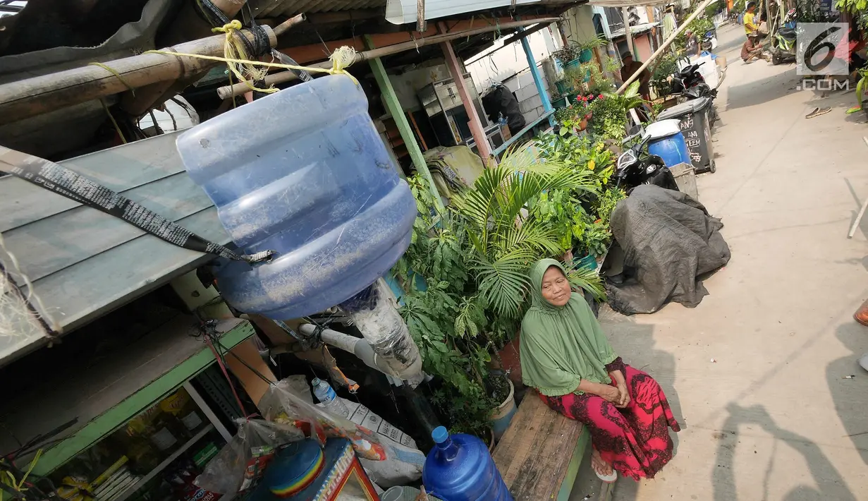 Warga duduk di bawah talang air kawasan Kampung Kamal Muara, Jakarta, Selasa (9/7/2019). Saat musim kemarau, warga Kampung Kamal Muara harus membeli air seharga Rp 5.000 per jeriken untuk kebutuhan mandi, cuci pakaian dan lain-lain. (Liputan6.com/Herman Zakharia)