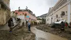 Orang-orang berjalan melalui lumpur di jalan yang banjir setelah hujan deras memicu tanah longsor yang meruntuhkan bangunan dan menyebabkan sebanyak 12 orang hilang, di Casamicciola, di pulau selatan Italia Ischia, Sabtu, 26 November 2022. Petugas pemadam kebakaran sedang melakukan upaya penyelamatan karena bala bantuan sedang dikirim dari Napoli terdekat, tetapi mengalami kesulitan dalam mencapai pulau baik dengan perahu motor atau helikopter karena cuaca. (AP Photo/Salvatore Laporta)