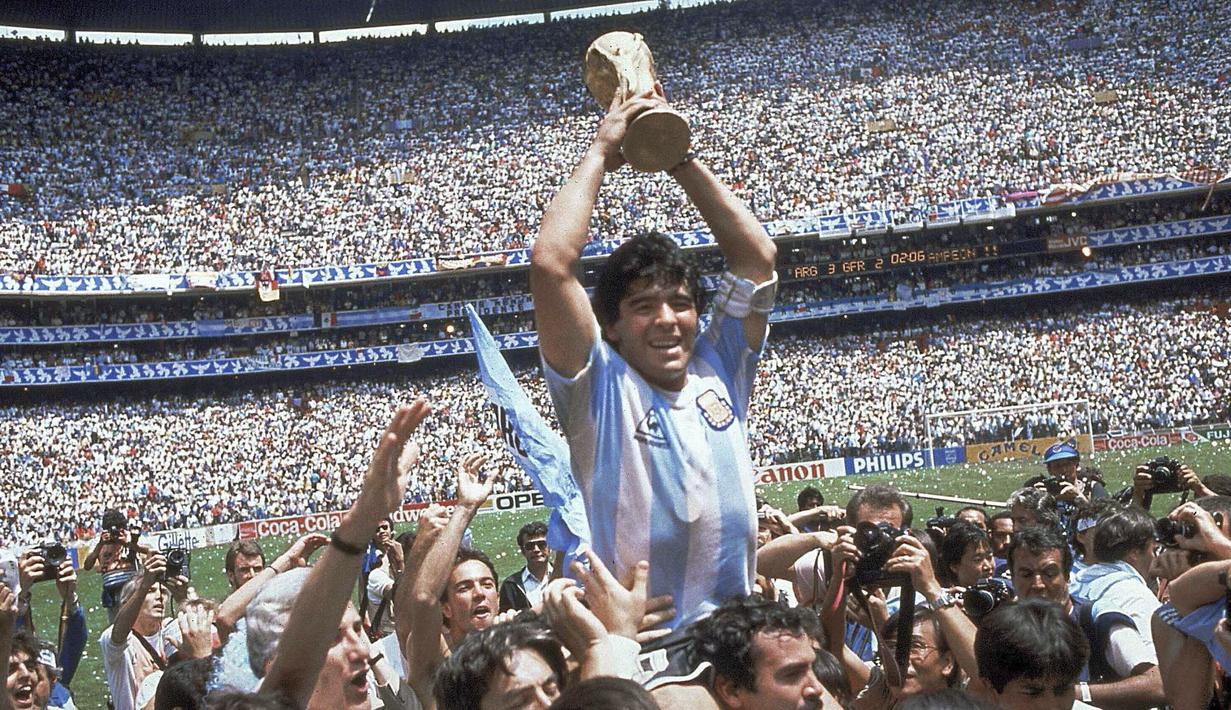 Penyerang Argentina, Diego Maradona, mengangkat trofi Piala Dunia saat usai mengalahkan Jerman Barat pada laga final Piala Dunia 1986 di Meksiko, (29/6/1986). (Photo by - / AFP)