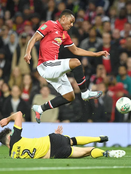 Pemain Manchester United, Anthony Martial (atas) melompat melewati adangan pemain Burton  Albion, Tom Flanagan pada laga Piala Liga Inggris di Old Trafford, Manchester (20/9/2017). MU menang 4-1. (AFP/Paul Ellis)