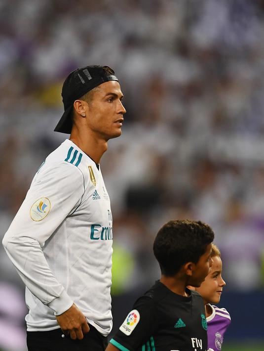 Cristiano Ronaldo bersama anaknya Cristiano Ronaldo Jr. berdiri menyaksikan penyerahan trofi Piala Super Spanyol di  Santiago Bernabeu stadium, Madrid, (16/8/2017). Real menang agregat 5-1. (AFP/Gabriel Bouys)