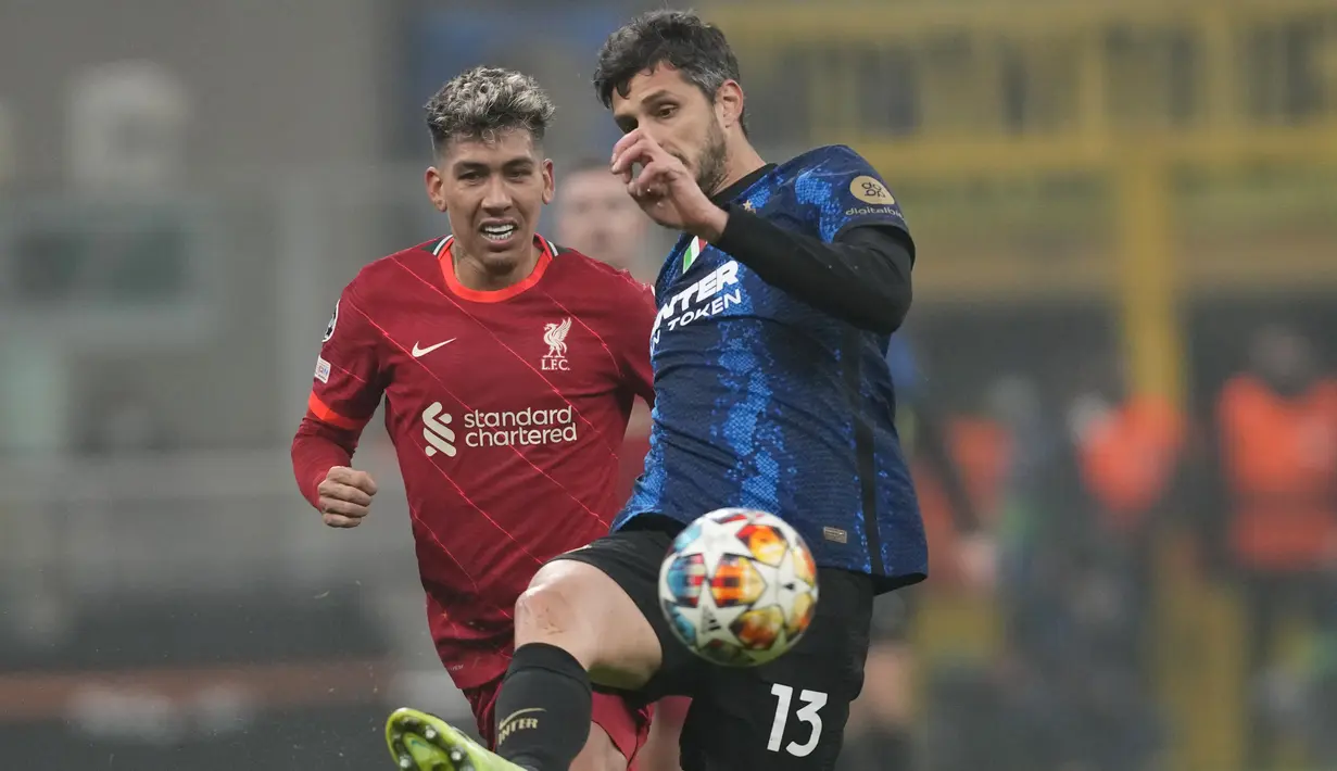 Bek Inter Milan Andrea Ranocchia berebut bola dengan penyerang Liverpool Roberto Firmino pada leg pertama babak 16 besar Liga Champions di Stadion Giuseppe Meazza, Milan, Kamis dini hari WIB (17/2/2022). Melawat ke markas Inter Milan,  Liverpool menang 2-0. (AP Photo/Antonio Calanni)