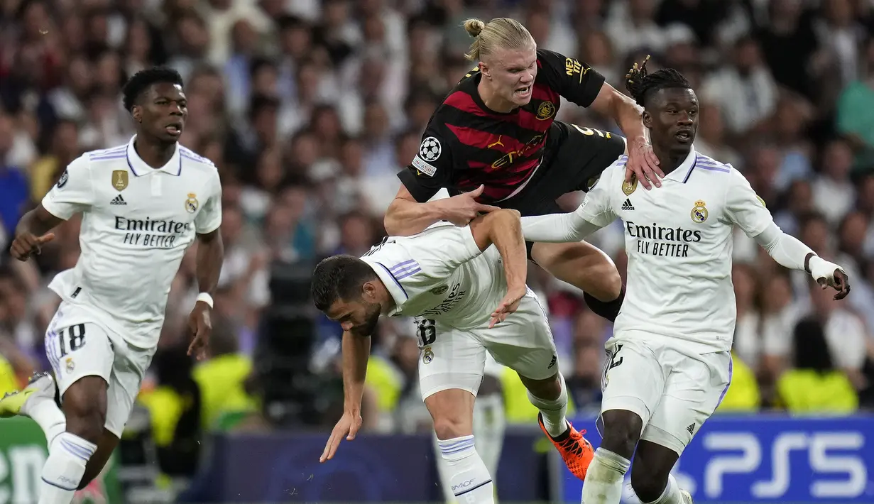 Pemain Manchester City, Erling Haaland (kanan kedua) terjatuh saat berebut bola dengan pemain Real Madrid, Eduardo Camavinga (kanan) dan Nacho pada laga leg pertama semifinal Liga Champions 2022/2023 di Santiago Bernabeu, Madrid, Rabu (10/05/2023) WIB. Laga berakhir dengan skor 1-1. (AP Photo/Manu Fernandez)