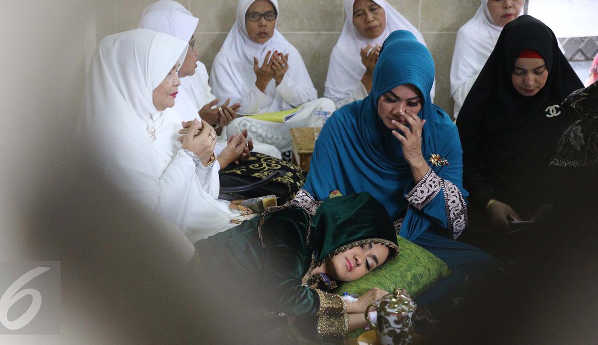 Julia Perez atau Jupe membaringkan tubuhnya di pangkuan ibunya, Sri Wulansih, disela acara pengajian di Kelapa Dua, Depok, Kamis (29/12). Bercucuran air mata,  Jupe minta didoakan sembuh dari kanker serviks yang diderita. (Liputan6.com/Herman Zakharia)