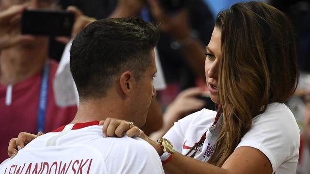 Kapten Polandia, Robert Lewandowski dihibur istrinya, Anna Lewandowska seusai dikalahkan Senegal pada pada penyisihan grup H di Piala Dunia 2018 di Stadion Spartak, Moskow, Selasa (19/6). Meski lebih diunggulkan, Polandia kalah 1-2. (FRANCK FIFE/AFP)