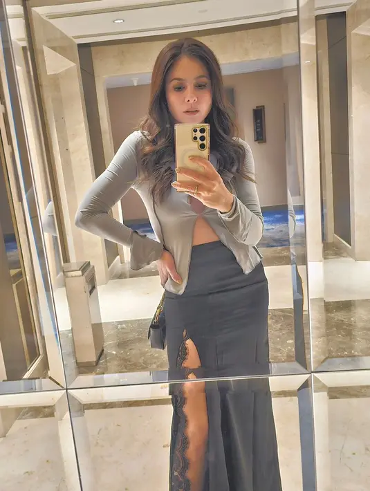 Di sini Wulan Guritno pamer mirror selfie yang memperlihatkan penampilan sempurnanya pakai tasan abu-abu lengan panjang dengan bagian tengah yang sedikit terbuka dan rok panjang berwarna hitam dengan detail high slit. [Foto: Instagram/wulanguritno]