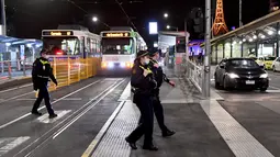 Petugas penegak hukum berpatroli di jalan-jalan selama aturan jam malam di Melbourne, pada Selasa (17/8/2021). Kota terbesar kedua di Australia itu memberlakukan pembatasan tinggal di rumah pada pukul 9 malam hingga 5 pagi untuK meredam lonjakan Covid-19 varian Delta. (William WEST/AFP)